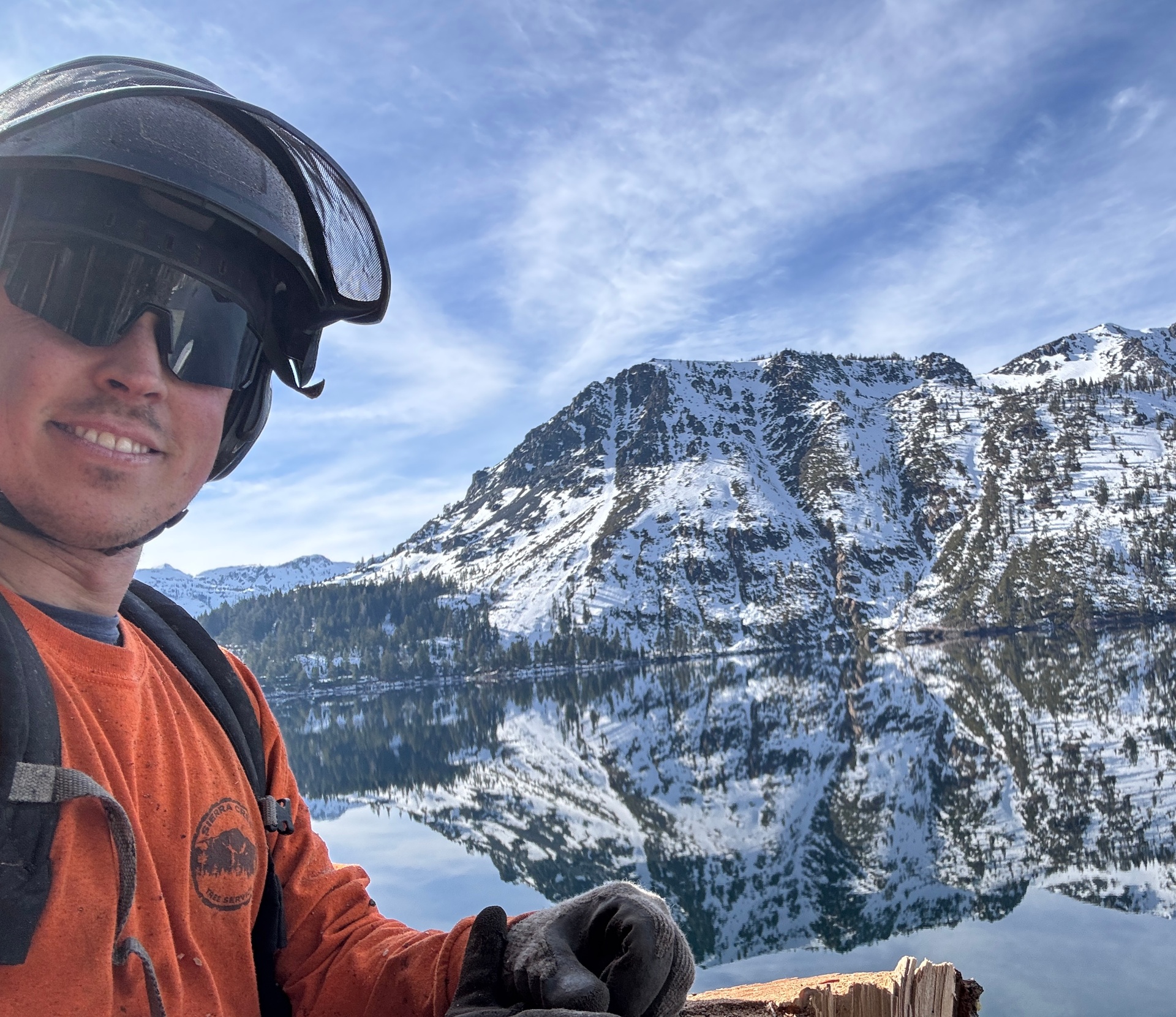 Leo Grasso, owner of Sierra Crest Tree Service, in climbing gear with Lake Tahoe mountains in the background